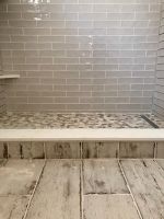Glass tiled walls, pebble look shower stall floor and unique plank look tiles for the floor, all come together for a warm country style at this northern Illinois waterfront remodel in 2017!