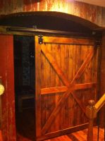 Hand crafted carriage door using reclaimed lumber opens to this Wisconsin homes media room.
